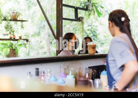 Frau Kundin in Gesichtsmaske geben Befehl an Kellnerin bei Cafe-Schalter Stockfoto