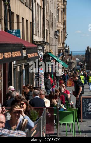 Menschen essen außerhalb Restaurants auf der Royal Mile, Edinburgh, Schottland. Stockfoto