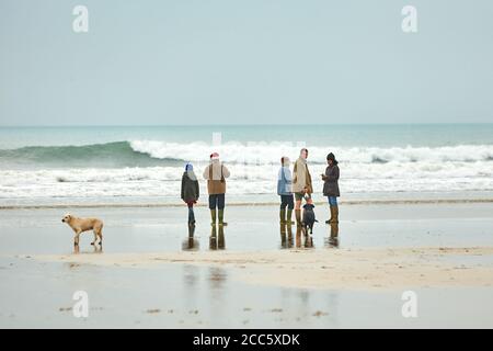 Menschen, die am Weihnachtstag am Perranporth Strand in Cornwall spazieren Stockfoto