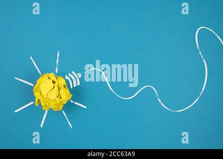 Glühbirne aus zerknittertem gelbem Papier auf blauem Hintergrund, Idee und Innovationskonzept Stockfoto