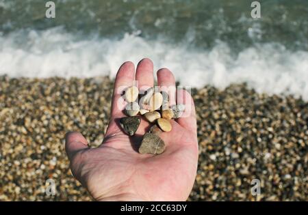 Kleine Strandsteine in der Hand am Meer Stockfoto