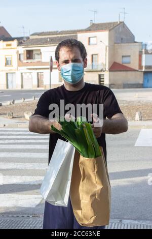 Delivery Mann in Schutzmaske und medizinische Handschuhe mit einem Papierbeutel. Service Quarantäne Stockfoto