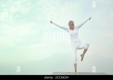 Frau macht Yoga-Übungen vor einem blauen Himmel Stockfoto