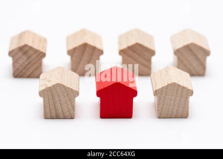 Winzige Holzspielzeughäuser in zwei Reihen, das in der Mitte rot bemalt, weißer Hintergrund Stockfoto