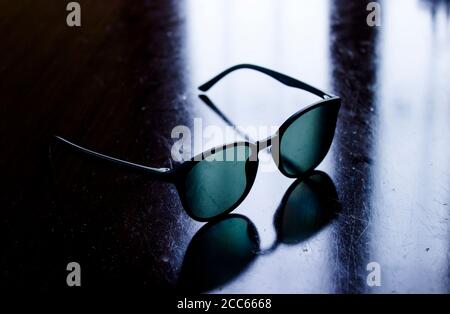 Vollformat-Bild einer Sonnenbrille mit rundem schwarzen Acetat-Rahmen, der auf zerkratzter, schmutziger Oberfläche steht. Brillen- und Schutzkonzept. Stockfoto