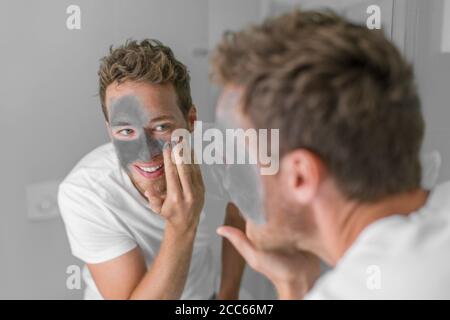 Männer Schönheit kaukasischen jungen Mann Anwendung Schlamm Ton Detox Maske auf Gesicht. Gesichtsbehandlung mit Holzkohle für die männliche Hautpflege Stockfoto