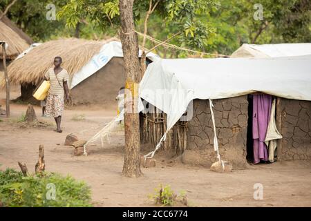 Flüchtlinge aus dem Südsudan leben in behelfsmäßigen, mit Planen bedeckten Lehmhäusern und Grasbüschel-Häusern in der Palabek-Flüchtlingssiedlung im Norden Ugandas, Ostafrika. Stockfoto