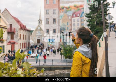 Quebecer Stadt Altstadt Frau Tourist fotografieren mit Telefon der berühmten Wandkunst Wandbild in Place Royale, Herbst Kanada Reise Stockfoto