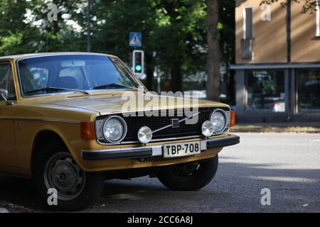 Klassischer alter gelber Volvo mit runden Scheinwerfern unter etwas Schatten mit einer grünen Ampel auf dem Hintergrund. Aufgenommen in Tampere Finnland. Stockfoto