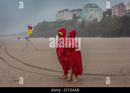 Tenby, Pembrokeshire, West Wales, Großbritannien. August 2020. Zwei RNLI-Rettungsschwimmer blicken auf das Meer und überwachen die Brandungswellen am Strand von Tenby, Pembrokeshire in West Wales. In der Nacht und am darauffolgenden Sommertag trafen Stürme und schlechtes Wetter Südengland und West Wales, Großbritannien, ein. Mittwoch, 19. August 2020. Tenby, Pembrokeshire, West Wales, UK Kredit: Jeff Gilbert/Alamy Live News Stockfoto