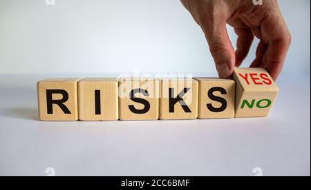 Hand dreht einen Würfel und ändert das Wort 'Nein' in 'Ja' oder umgekehrt. Wort „Risiken“. Schöner weißer Hintergrund, Kopierbereich. Geschäftskonzept. Stockfoto