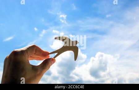 Mann Hand hält hölzernen Vogel auf Wolke Himmel Hintergrund. Die Entwicklung der Phantasie, kopieren Raum. Stockfoto