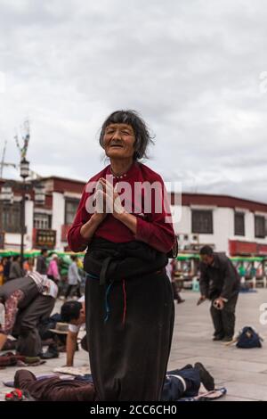 Lhasa, China - 21. Juni 2012 - Alte tibeterin, die am 21. Juni 2012 auf dem Platz vor dem Jokhang-Tempel in Lhasa, Tibet, China betet Stockfoto