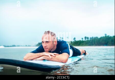 Mann Surfer liegt auf Surfbrett liegen Stockfoto