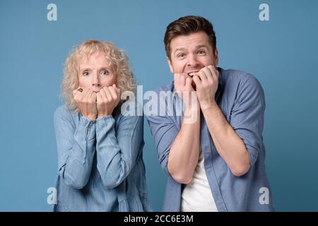 Mann und Frau bedecken den Mund mit ihren Händen, die Angst haben, Nägel zu beißen. Stockfoto