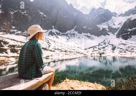 Junge genießen Sie mit zarten Sonnenschein sitzen auf Holzbank in der Nähe Der schöne Bergsee Stockfoto