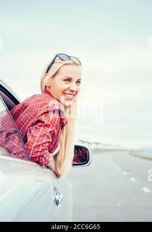 Glücklich lächelnde junge Frau schaut aus dem Autofenster Stockfoto