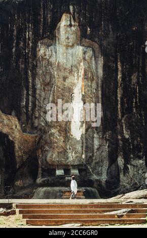 Eine kleine Frauenfigur steht am Fuße des ältesten Buddha-Idols in Sri Lanka Stockfoto