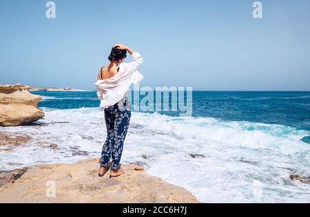 Frauen in leichter Kleidung bleiben an der windigen Küste Stockfoto