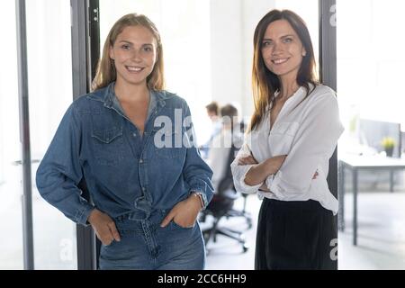 Zwei weibliche Kollegen nebeneinander stehen in einem Büro. Stockfoto