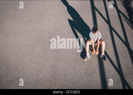 Allein langweiliger Junge sitzt auf dem Skateboard Stockfoto