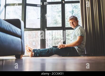 Student arbeitet mit Laptop auf dem Boden in der Nähe der großen sitzen Angezeigt Stockfoto