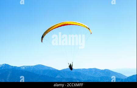 Gleitschirmfliegen im Himmel über den blauen Bergen Stockfoto