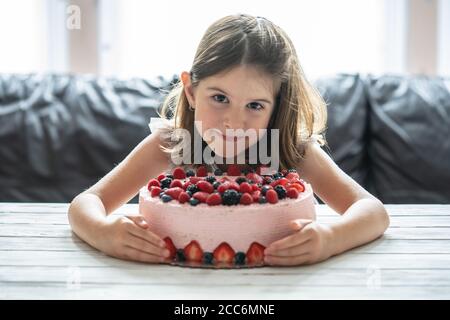 Kleine Mädchen Geburtstagstorte.Home Kuchen mit Beeren gemacht. Kuchen mit Erdbeere, Brombeere, Heidelbeere und Himbeere auf dem Tisch Stockfoto