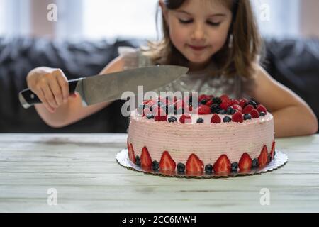 Kleine Mädchen Geburtstagstorte.Home Kuchen mit Beeren gemacht. Kuchen mit Erdbeere, Brombeere, Heidelbeere und Himbeere auf dem Tisch Stockfoto