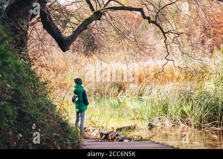 Junge bleiben unter großen Baum in der Nähe des Teiches im Herbst parken Stockfoto