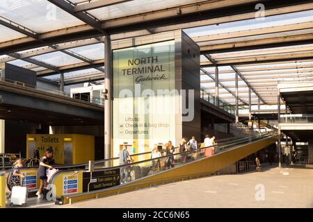 Reisende betreten den Nordterminal des Flughafens London Gatwick im Vereinigten Königreich. Sie fahren mit einem Förderband in den Abflugbereich. Stockfoto