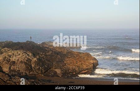 Ein Mann steht auf einem Aussichtspunkt über dem Pazifischen Ozean entlang eines Pfades am Meer in der kleinen Stadt Yachats, Oregon, an der Pazifikküste von Oregon. Stockfoto