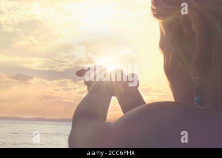 Ein neuer Tag beginnt mit dem Sonnenaufgang geschützt in der Hände einer Frau Stockfoto