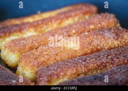 Fischfinger braten auf Bratpfanne mit goldener knuspriger Beschichtung, Nahaufnahme mit enger Schärfentiefe Stockfoto