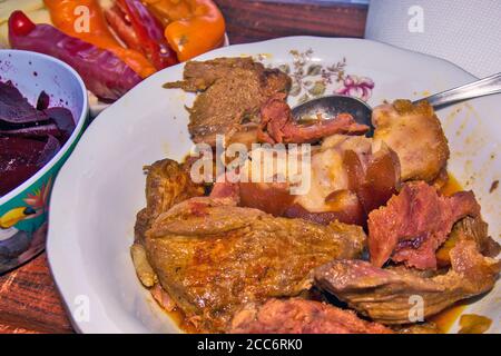 Mittagessen auf einem Teller mit verschiedenen Fleischsorten und Salaten von Paprika und Rüben. Stockfoto