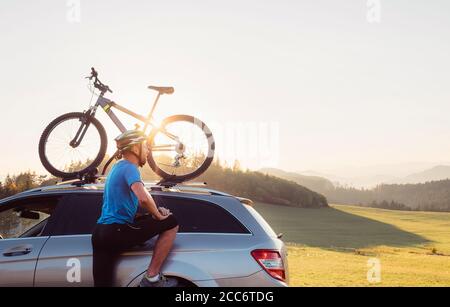 Der Mann kam mit dem Auto in den Berg mit seinem Fahrrad auf dem Dach. Mountainbike-Konzept Stockfoto