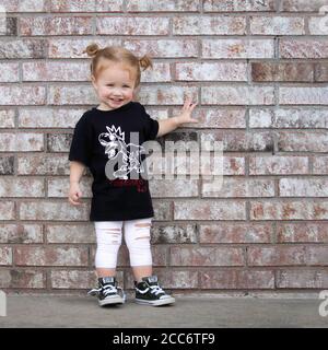 Kleines Mädchen in grunge Punk Kleidung posiert auf Backsteinmauer Stockfoto