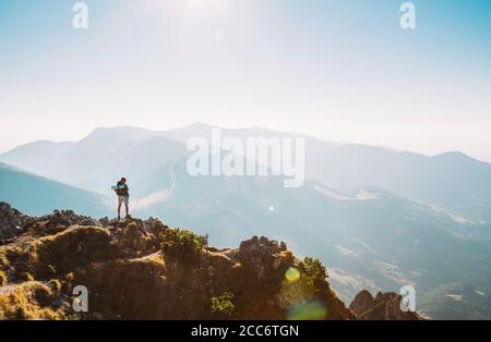 Bergwanderer mit Rucksack winzige Figur Aufenthalt auf Berggipfel mit schönem Panorama Stockfoto
