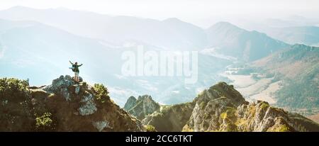 Bergwanderer mit Rucksack kleine Figur steht auf Berggipfel mit schönem Panorama Stockfoto