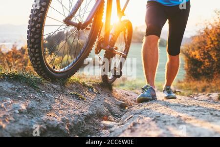 Junger Radfahrer Mann schob ein Mountainbike den Hügel hinauf Bild aus der Nähe. Aktive Abenteuerreise mit dem Fahrrad. Stockfoto