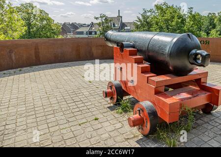 Rückansicht einer alten schwarzen Feuerkanone auf einem orangefarbenen Holzsockel auf dem Rondeel (De Vijf Koppen), der alten Stadtmauer von Maastricht Stockfoto