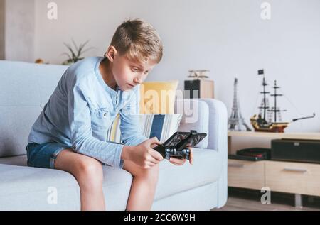 Teenager Junge begeistert spielt auf der Spielkonsole mit verbunden Smartphone Stockfoto