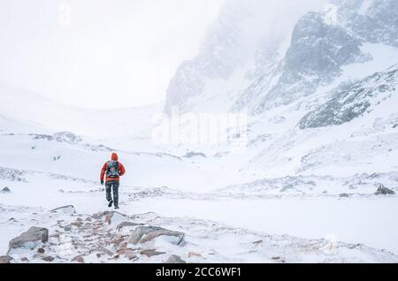 Ein Kletterer geht allein in hohen Bergen in windigen Schnee Wetter Stockfoto