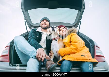 Vater und Sohn mit Beagle Hund sitzen zusammen im Kofferraum. Lange Auto-Reise Pause. Stockfoto