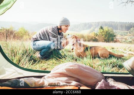 Frau und ihr Hund zärtliche Szene in der Nähe des Zeltzeltes. Aktive Freizeit, Reisen mit Haustier einfache Dinge Konzept Bild Stockfoto