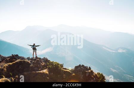 Bergwanderer mit Rucksack kleine Figur steht auf dem Berggipfel Stockfoto