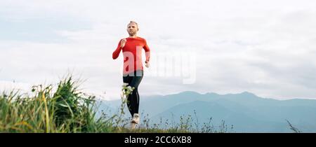 Mann in roten Langarm-Shirt läuft an der Straße mit Berg Hintergrund gekleidet Stockfoto