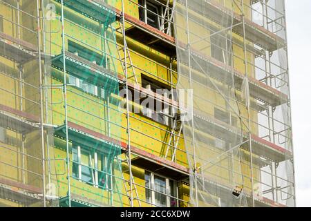 Gerüst und Sicherheitsnetz rund um das Haus zu installieren thermische Isolierung der Fassade des Mehrfamilienhauses Stockfoto