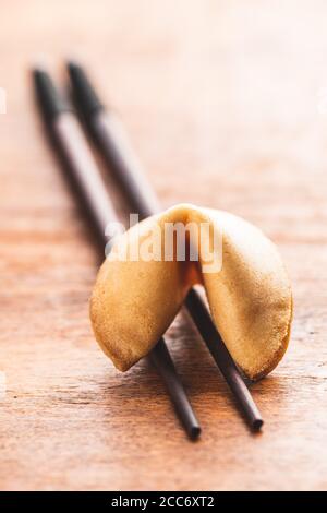 Chinesische Glücksplätzchen. Glücksplätzchen auf Essstäbchen auf Holztisch. Stockfoto