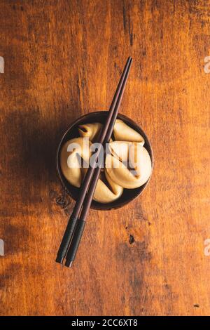 Chinesische Glücksplätzchen. Glücksplätzchen mit Essstäbchen in Holzschüssel. Draufsicht. Stockfoto